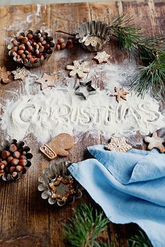 a wooden table topped with christmas cookies and other holiday decorations on top of snow covered ground