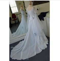 a white wedding dress on display in front of a mirror