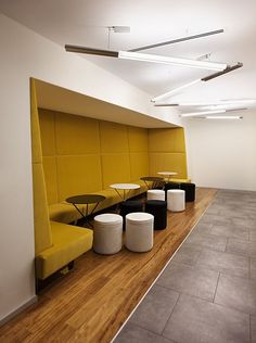 an empty room with tables and stools next to a yellow bench on the floor