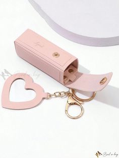 a pink heart shaped keychain is sitting next to a box with a pair of scissors in it