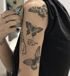 a woman is taking a selfie with her phone and butterfly tattoos on her arm