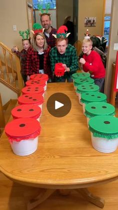 a group of people standing around a table with cupcakes on top of it