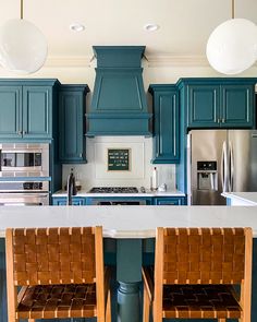 a kitchen with blue cabinets and two chairs in front of the counter top, next to an island