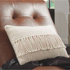 a brown leather chair with a white pillow on it