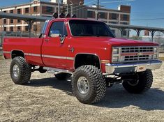 a red pickup truck parked on top of a dirt field