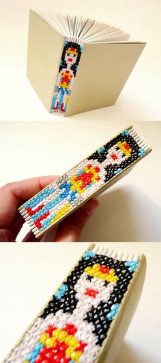 a bookmark made out of bead and paper is being held by someone's hand