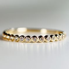 a yellow gold ring with five round diamonds on the inside and outside, sitting on a white surface