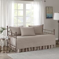 a living room with a daybed, lamp and rug in front of the window