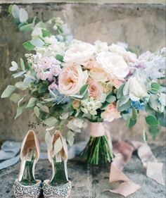 the bride's bouquet and high heeled shoes are sitting on the stone floor