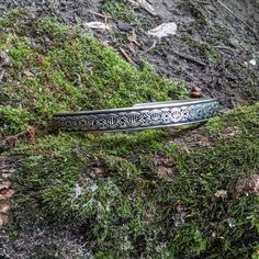 a silver bracelet sitting on top of a moss covered hill