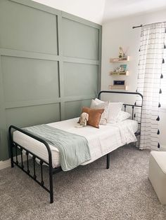 a bedroom with a metal bed frame and green painted paneling on the wall behind it