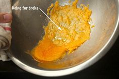 a metal bowl with some food in it and an orange substance on the bottom that has been melted