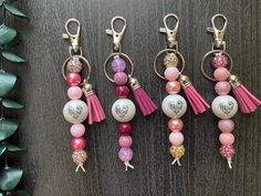 four key chains with different designs and colors on them, one has a tassel hanging from it's side