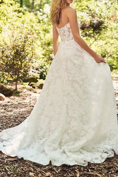 a woman in a white wedding dress standing on the ground with her back to the camera