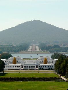 a large white building sitting on top of a lush green field next to a lake