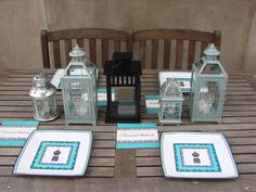 the table is set with teal and white place mats, candles, and lanterns