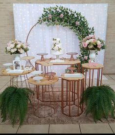 a table set up with vases, plates and flowers on it in front of a backdrop