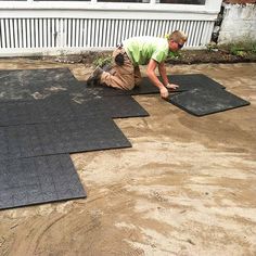 a man laying on the ground next to two black mats with one person working on it