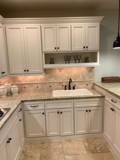 a kitchen with white cabinets and marble counter tops