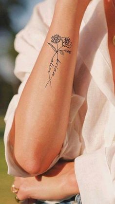 a woman's arm with a flower tattoo on her left arm and the word love written in cursive writing