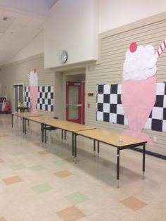 an empty school hallway with tables and checkered flooring on the walls, decorated with ice cream cones