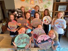 a group of girls holding up signs in front of a cake