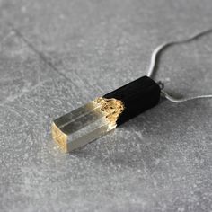 a black and gold necklace on a silver chain with a square pendant hanging from it's end