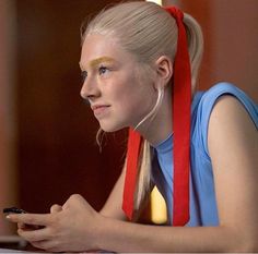 a woman sitting at a table with a cell phone in her hand and headbands around her neck