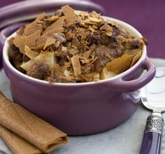 a purple bowl filled with food on top of a table next to some cinnamon sticks