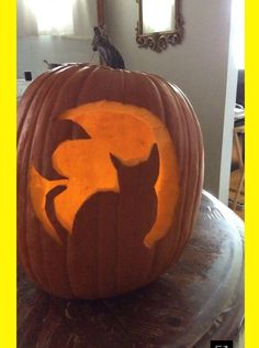 a carved pumpkin with an image of a cat on it's face in front of a mirror