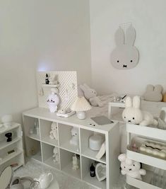 there are many stuffed animals on the shelves in this child's room, all white