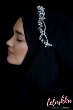 a woman wearing a black hijab with pearls on it