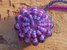 a close up of a purple and black object on a wooden surface with some string