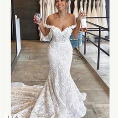 a woman in a white wedding dress holding up a drink and posing for the camera