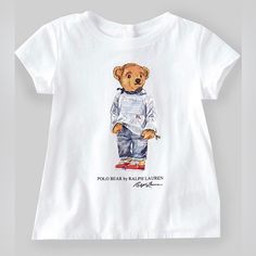 Polo By Ralph Lauren T-Shirt Features Cap Sleeves, Ribbed Crewneck, 3 Buttoned Placket At The Center Back, Straight Hem, Polo Mascot Bear By Ralph Lauren Dressed In Iconic Flag Sweater And Patchwork Jeans, Polo Bear By Ralph Lauren And Ralph Lauren Script At Front Chest Cotton T-shirt With Cartoon Print For Playwear, Cotton Tops With Letter Print For Playwear, Cotton Tops With Character Print For Playwear, Cotton Graphic Print Shirt For Playwear, Short Sleeve Cotton Tops For Playwear, Graphic Tee Tops With Letter Print For Playwear, Casual Tops With Character Print For Playtime, Short Sleeve Tops With Cartoon Print For Playwear, Graphic Tee Crew Neck Tops For Playwear