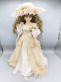 a doll with long hair wearing a white dress and bonnet on top of her head