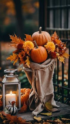 pumpkins and flowers in a basket next to a lantern