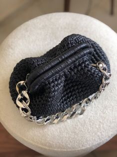 a black purse is on top of a white hat with chains hanging from it's sides