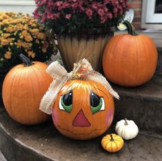 three pumpkins with faces painted on them sitting on the steps