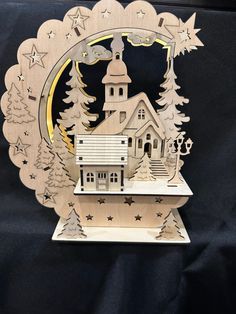 a laser cut christmas ornament with a church in the middle and trees around it