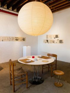 a room with a table and two stools under a large light fixture on the wall