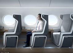 a man sitting on an airplane seat in front of two windows and looking out the window