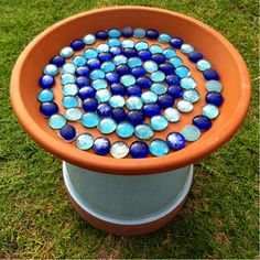 an orange bowl with blue and white glass balls in it sitting on top of a green lawn