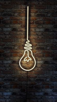 a neon light bulb hanging from the side of a brick wall