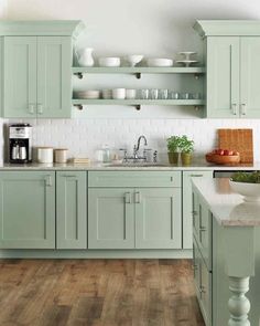 a kitchen filled with lots of green cupboards and counter top space next to a wooden floor