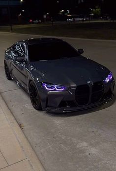 a car parked on the side of a road at night with its headlights turned purple