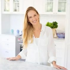 a woman standing in front of a counter with her hands on the counter and smiling at the camera