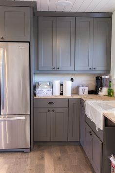 a kitchen with gray cabinets and white counter tops