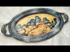 a blue tray with three birds painted on the front and back of it, sitting on a white tablecloth