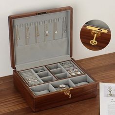 an open wooden box with jewelry inside on a table next to a piece of paper